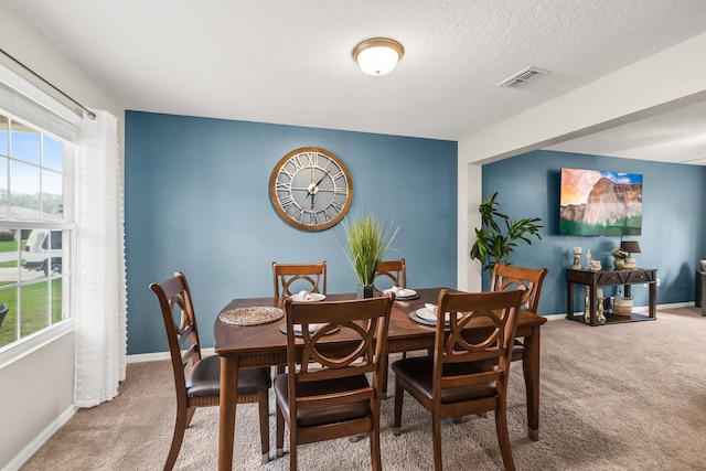 carpeted dining room featuring a textured ceiling