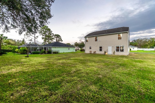 back of house with a lanai and a lawn