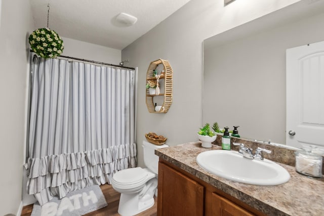 bathroom with a shower with shower curtain, vanity, a textured ceiling, hardwood / wood-style flooring, and toilet