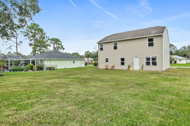 rear view of house with a lawn and glass enclosure