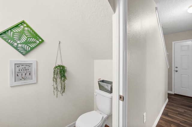 bathroom with hardwood / wood-style flooring, toilet, and a textured ceiling