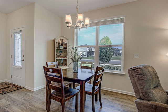 dining area featuring a healthy amount of sunlight, wood-type flooring, and a chandelier