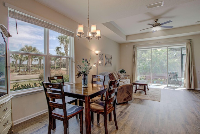 dining space featuring ceiling fan with notable chandelier and wood-type flooring