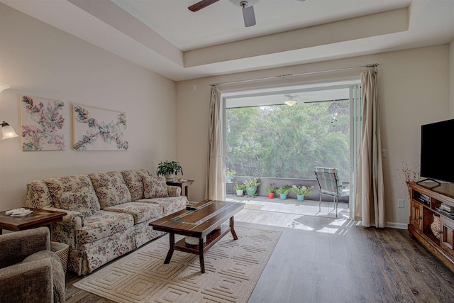 living room featuring a tray ceiling, ceiling fan, and wood-type flooring