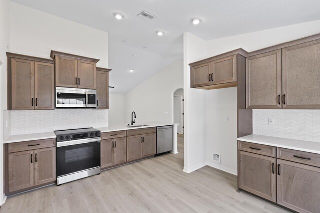 10 Reine Pl, Palm Coast, FL 32164 - kitchen with appliances with stainless steel finishes, a sink, arched walkways, light wood-style floors, and tasteful backsplash