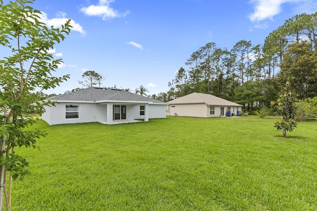 10 Reine Pl, Palm Coast, FL 32164 - back of property featuring a lawn, stucco siding, and roof with shingles