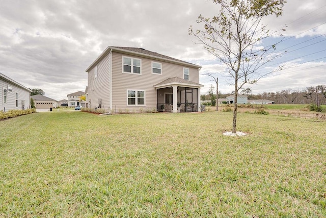 rear view of house featuring a yard and a sunroom