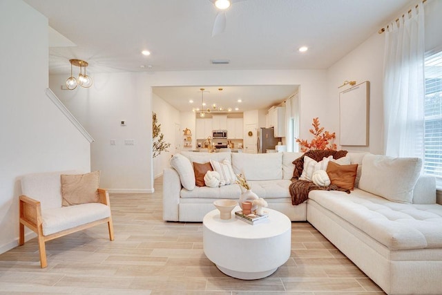 living room with a wealth of natural light, an inviting chandelier, and light hardwood / wood-style flooring