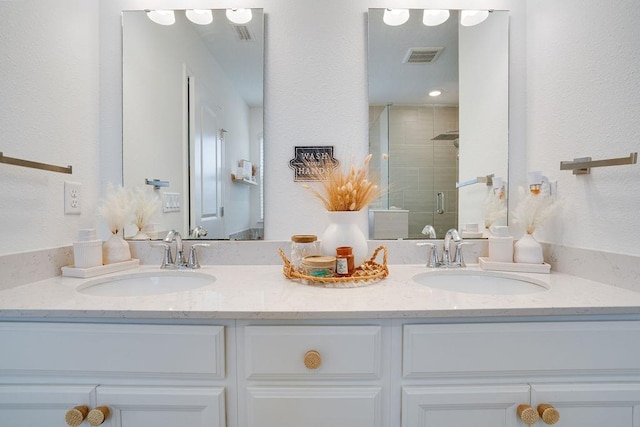 bathroom featuring a shower with shower door and vanity