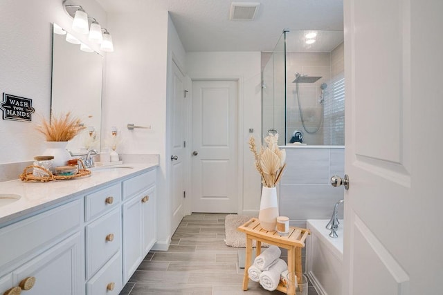 bathroom with plus walk in shower, wood-type flooring, and vanity