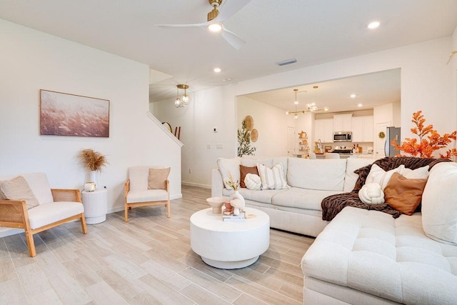 living room with ceiling fan and light hardwood / wood-style flooring