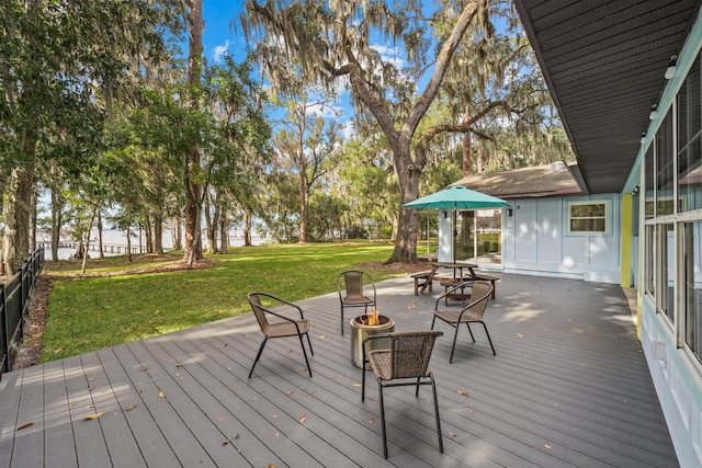 wooden terrace with a fire pit and a yard