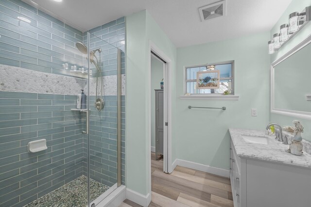 bathroom with walk in shower, wood-type flooring, vanity, and ceiling fan