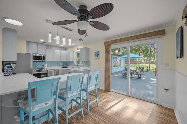 kitchen featuring a peninsula, a sink, light countertops, ornamental molding, and appliances with stainless steel finishes