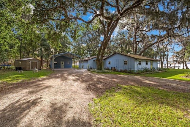 view of front facade featuring a carport, a storage shed, and a front lawn