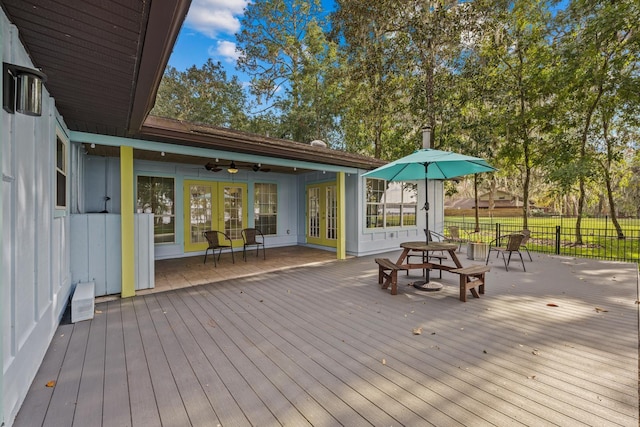 wooden terrace with ceiling fan, french doors, and fence