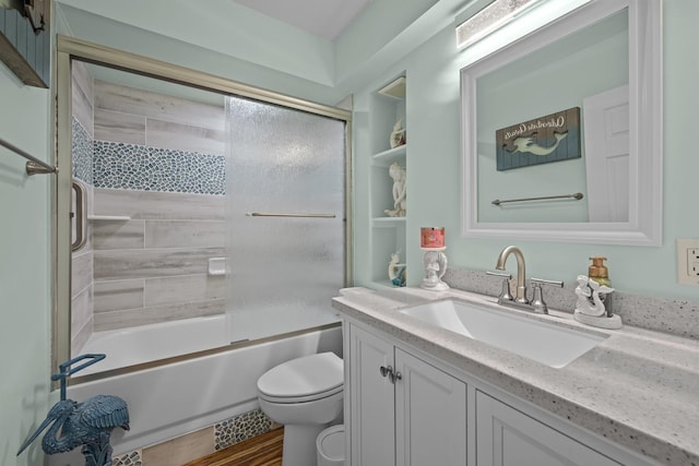 full bathroom featuring hardwood / wood-style floors, vanity, toilet, and combined bath / shower with glass door