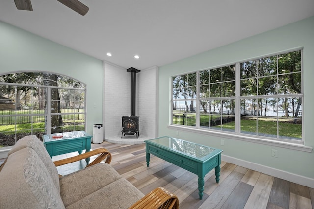 living room with a wood stove, ceiling fan, and light wood-type flooring