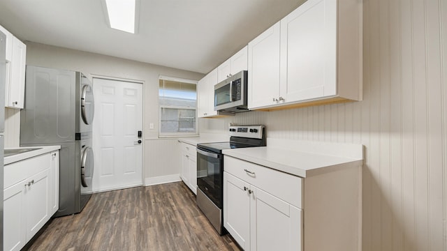 kitchen with white cabinetry, stainless steel appliances, dark wood-type flooring, and stacked washer and clothes dryer