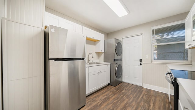 laundry room with wood walls, stacked washer and dryer, dark wood-type flooring, and sink