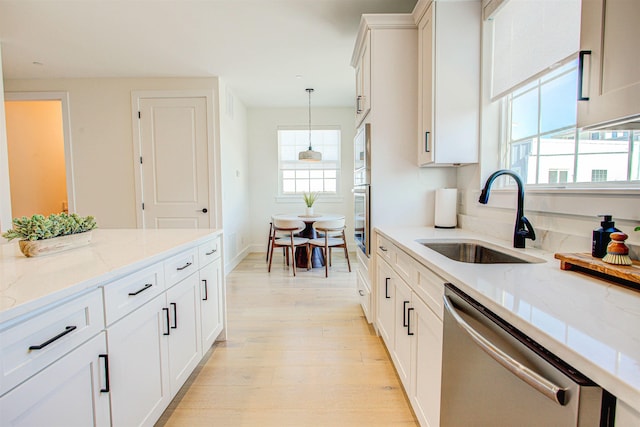 kitchen featuring appliances with stainless steel finishes, sink, white cabinets, hanging light fixtures, and light stone countertops