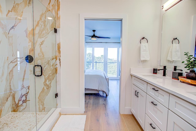 bathroom with wood-type flooring, vanity, ceiling fan, and a shower with shower door