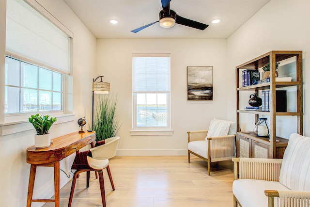 living area with ceiling fan, light wood-type flooring, and a wealth of natural light