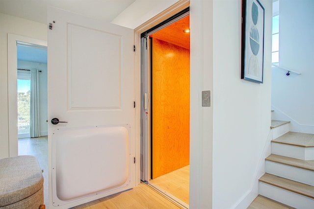 hallway featuring elevator and light hardwood / wood-style flooring