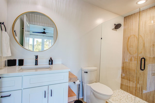 bathroom with toilet, a shower with shower door, tile walls, vanity, and ceiling fan