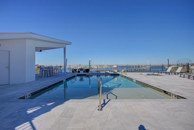 view of swimming pool with a patio, a water view, and ceiling fan