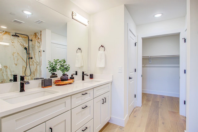 bathroom featuring wood-type flooring, a tile shower, and vanity