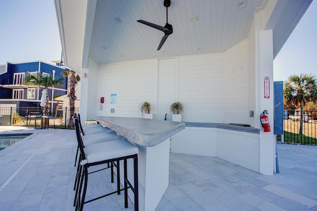 view of patio with ceiling fan and a bar