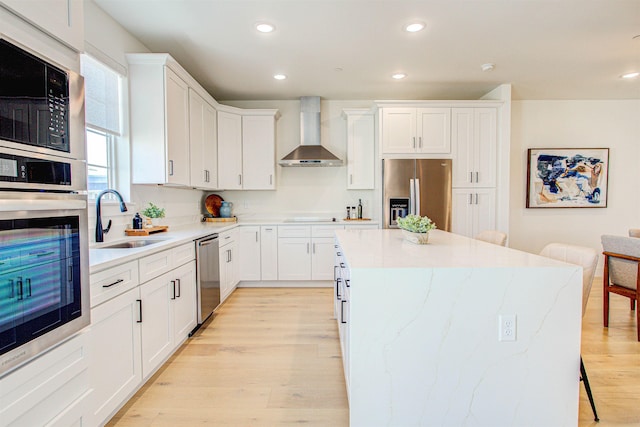 kitchen with white cabinetry, wall chimney range hood, black appliances, and sink