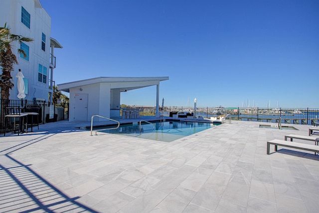 view of swimming pool featuring a patio and a water view