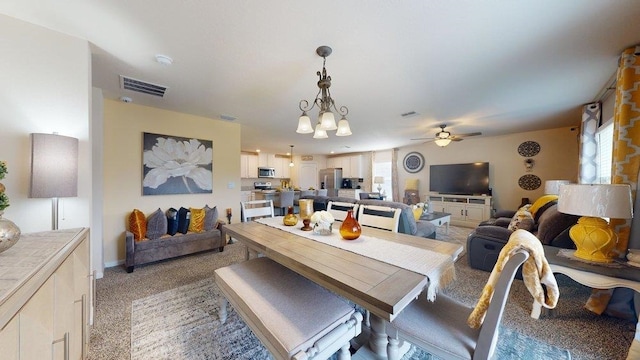 dining room featuring carpet flooring and ceiling fan with notable chandelier