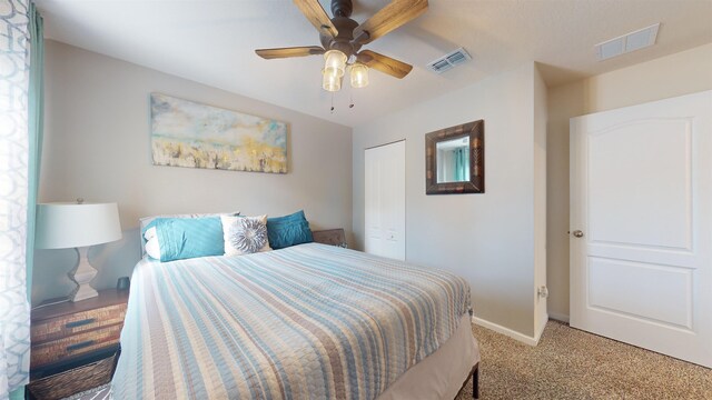 bedroom featuring a textured ceiling, light colored carpet, a closet, and ceiling fan