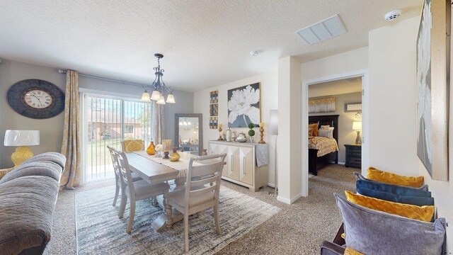 carpeted dining area featuring an inviting chandelier