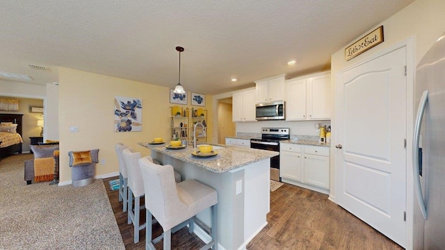 kitchen featuring white cabinetry, hanging light fixtures, stainless steel appliances, and sink