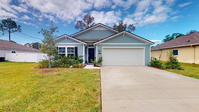 view of front of house with a front lawn, an attached garage, fence, and driveway