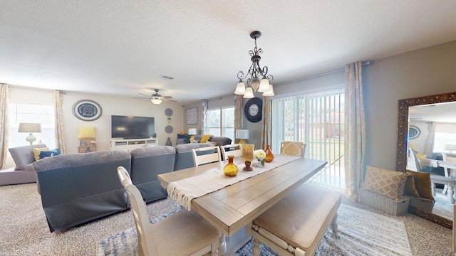 carpeted dining space featuring a textured ceiling and ceiling fan with notable chandelier