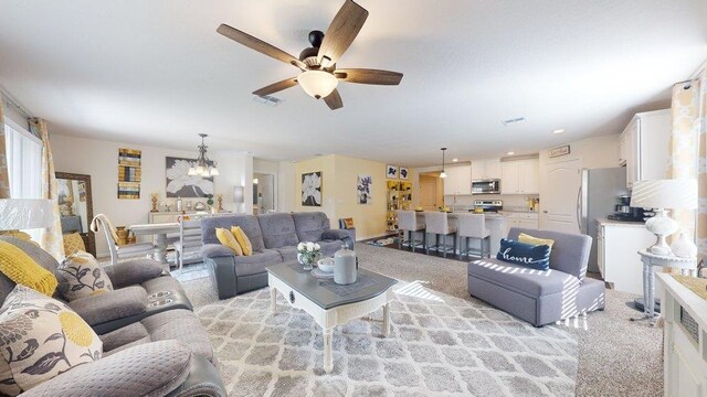 carpeted living room featuring ceiling fan and a textured ceiling