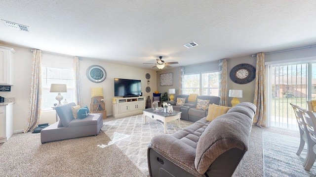 carpeted living room featuring ceiling fan and a textured ceiling