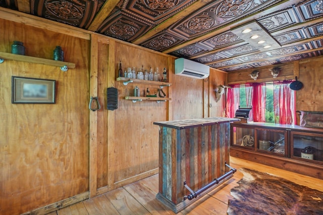 bar featuring light hardwood / wood-style floors, a wall unit AC, and wooden walls