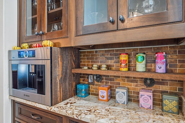 bar featuring tasteful backsplash, light stone counters, and oven