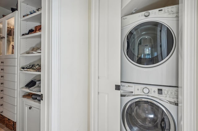 clothes washing area with stacked washing maching and dryer