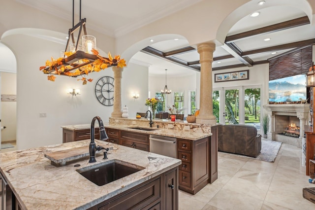 kitchen featuring dishwasher, sink, light stone countertops, and an island with sink