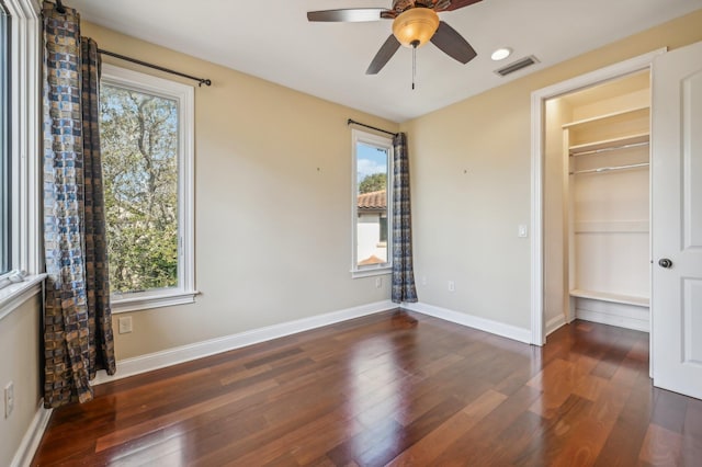 unfurnished bedroom with a walk in closet, ceiling fan, a closet, and dark hardwood / wood-style floors