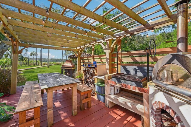 wooden terrace featuring a pergola, a grill, a lawn, and an outdoor fire pit