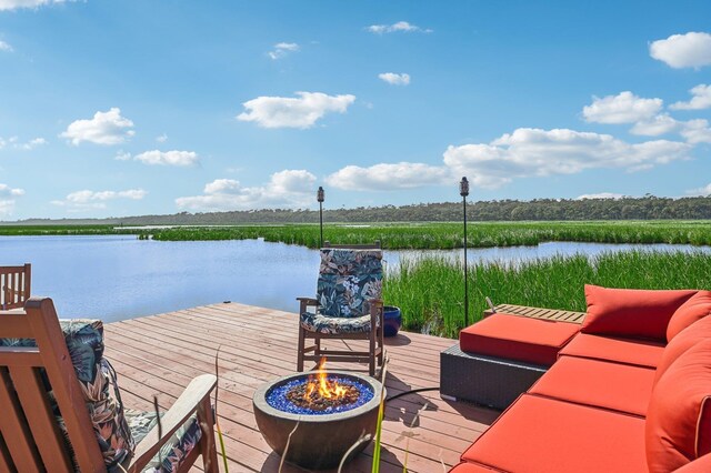 view of dock featuring a water view and an outdoor living space with a fire pit