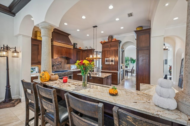 kitchen with light stone counters, backsplash, kitchen peninsula, pendant lighting, and appliances with stainless steel finishes